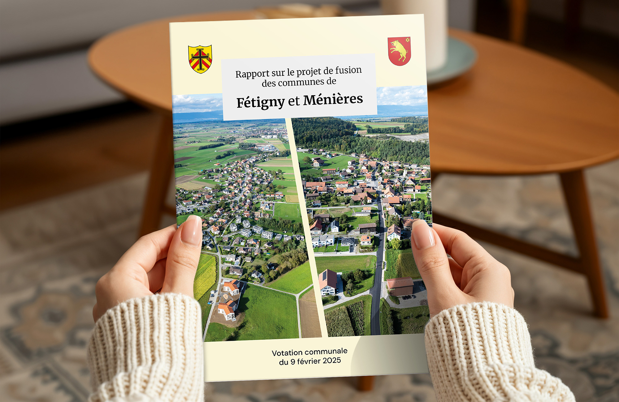 des mains tiennent une brochure A4 fermée du projet de fusion des communes de Fétigny et de Ménières